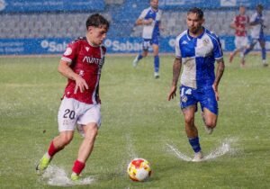 Diego Gómez conduce el balón en el césped encharcado de la Nova Creu Alta. LOF
